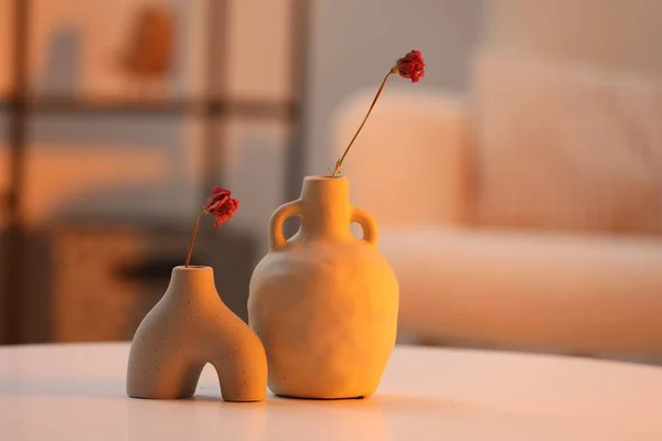 Vases with dried flowers on table in living room. Home-like cozy atmosphere at sunset
