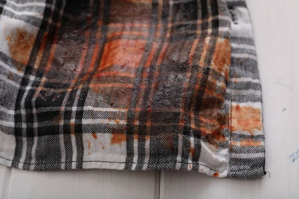 Shirt with stain of sauce on white wooden table, closeup