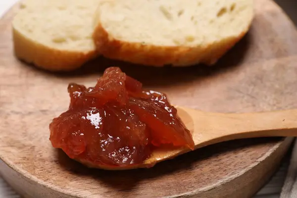 Delicious apple jam and bread slices on wooden board, closeup