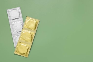Açık yeşil arka planda paketli prezervatifler, metin için yeri olan üst görünüm. Güvenli seks.