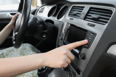 Favori radyoyu seçiyorum. Arabadaki ses düğmesine basan kadın, kapat
