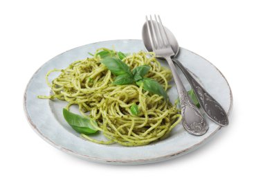 Beyaz arka planda pesto soslu lezzetli makarna, fesleğen ve çatal bıçak.