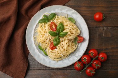 Peynirli, domatesli, fesleğenli, ahşap masadaki lezzetli makarna.