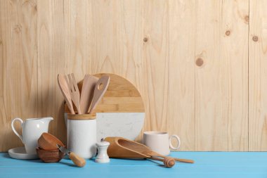 Açık mavi masada, ahşap arkaplan ve metin için farklı mutfak gereçleri kümesi