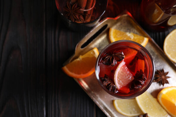 Glass of aromatic punch drink and ingredients on wooden table, flat lay. Space for text