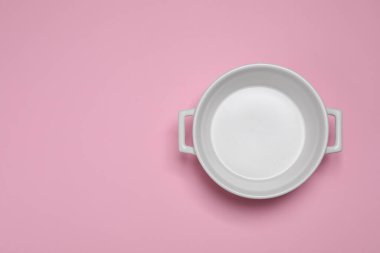 Pembe arka planda beyaz tencere, üst manzara. Metin için boşluk