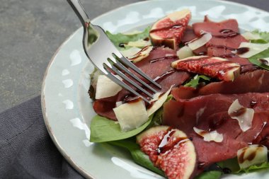 Gri masada nefis bresaola salatası yiyorum, yakın plan.