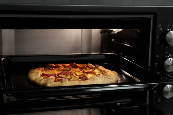 Baking delicious pie in electric oven, closeup