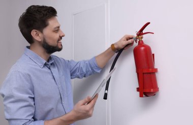Tabletli adam yangın söndürücüyü içeride kontrol ediyor.