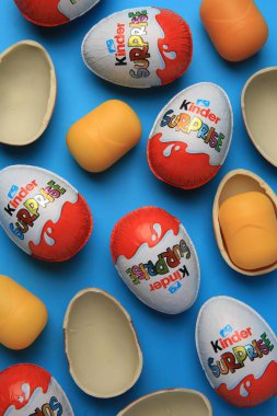 Sveti Vlas, Bulgaristan - 29 Haziran 2023: Açık mavi zemin üzerinde Kinder Sürpriz Yumurtalar ve plastik kapsüller, düz yatar