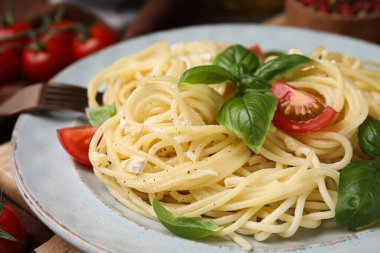 Delicious pasta with brie cheese, tomatoes and basil leaves on table, closeup