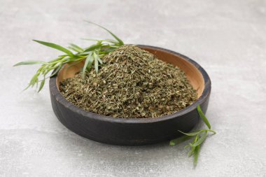 Açık gri desenli masada kuru ve taze tarhun otu.