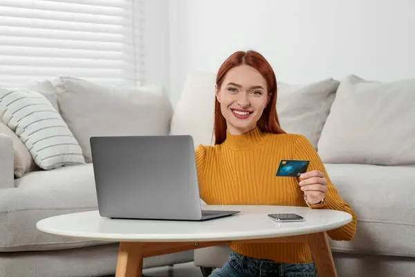 Happy woman with credit card using laptop for online shopping at home