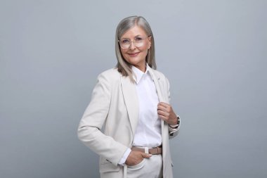 Gri arka planda gözlüklü güzel yaşlı kadın portresi.