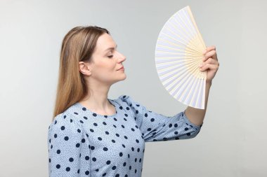 Gri arka planda serinlemek için el sallayan güzel bir kadın.