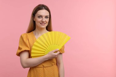 Sarı elli mutlu kadın pembe arka planda yelpaze, mesaj için boşluk