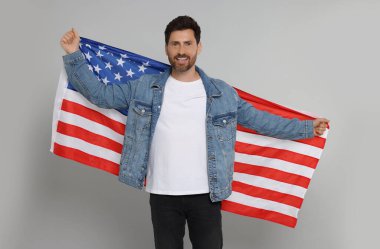 4 Temmuz - ABD 'nin Bağımsızlık Günü. Gri arka planda Amerikan bayrağı taşıyan mutlu adam