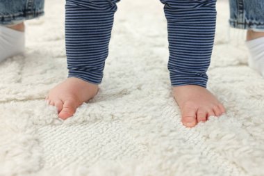 Anne ve bebek yumuşak halıda duruyor, yakın plan.