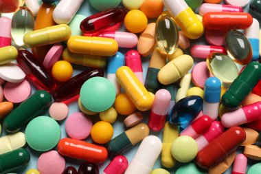 Açık mavi arka planda bir sürü farklı hap var.