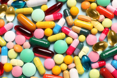 Açık mavi arka planda bir sürü farklı hap var.