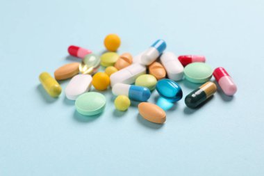 Açık mavi arka planda birçok farklı hap, yakın plan