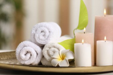 Spa kompozisyonu. Yanan mumlar, tesisat çiçeği, tepside yeşil yapraklar ve havlular, yakın plan.