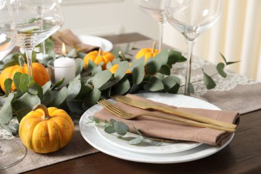 Güzel bir sonbahar sofrası. Tabaklar, çatal bıçak, gözlük, balkabağı ve çiçek dekoru.