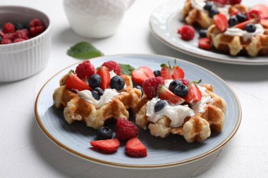 Lezzetli Belçika waffleları, taze böğürtlen ve beyaz masada krem şanti.