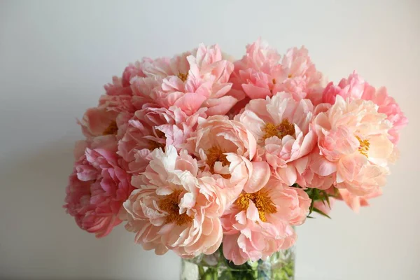 Beautiful pink peonies in vase near white wall