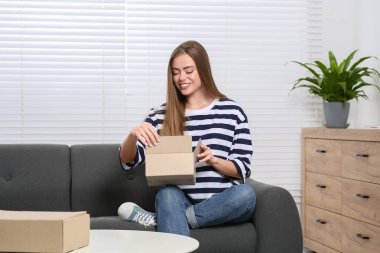 Evde paketleri açan mutlu kadın. Çevrimiçi mağaza