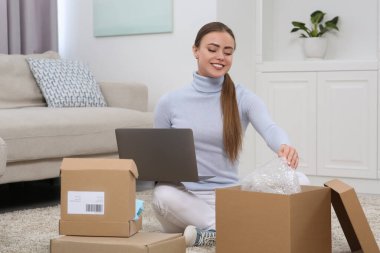 Evde paketleri açan mutlu kadın. Çevrimiçi mağaza