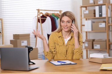 Satıcı ofiste çalışırken telefonla konuşuyor. Çevrimiçi mağaza