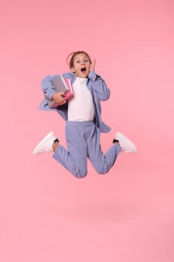 Pembe arka planda zıplayan kitaplarla mutlu liseli kız