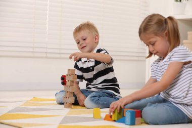 Küçük çocuklar içeride yapı taşlarıyla oynuyorlar. Tahta oyuncaklar