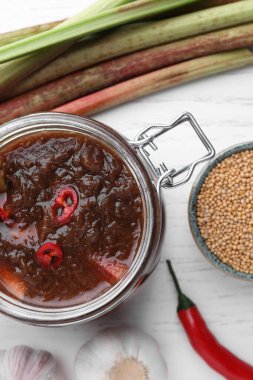 Düz kompozisyon, lezzetli ravent sosu ve beyaz ahşap masa üzerindeki malzemeler.