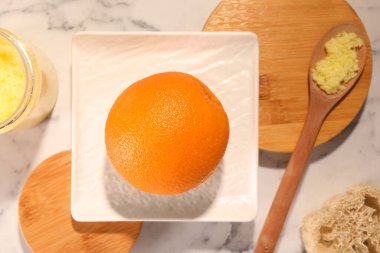 Turuncu, doğal vücut fırçası ve beyaz mermer masa üzerinde luffa, düz yatak. Selülit karşıtı tedavi