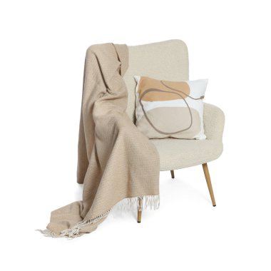 Beyaz üzerinde battaniyesi ve yastığı olan şık rahat bir koltuk.