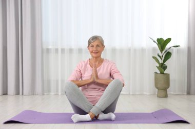 Mutlu son sınıf öğrencisi kadın evde yoga yapıyor.