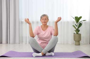 Son sınıf öğrencisi kadın evde yoga yapıyor.