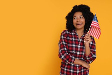 4 Temmuz - ABD 'nin Bağımsızlık Günü. Sarı arka planda Amerikan bayrağı olan mutlu kadın, mesaj için boşluk