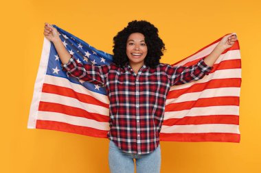 4 Temmuz - ABD 'nin Bağımsızlık Günü. Sarı arka planda Amerikan bayrağı taşıyan mutlu kadın.