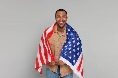 4 Temmuz - ABD 'nin Bağımsızlık Günü. Açık gri arka planda Amerikan bayrağı taşıyan mutlu adam