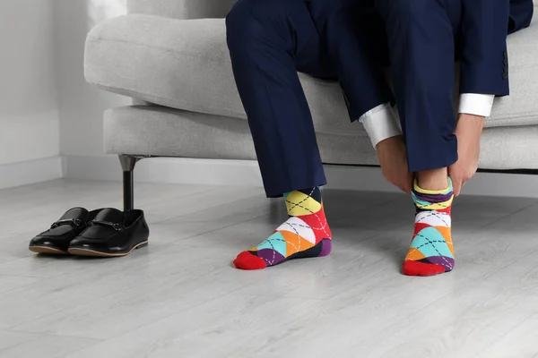 Man putting on colorful socks at home, closeup