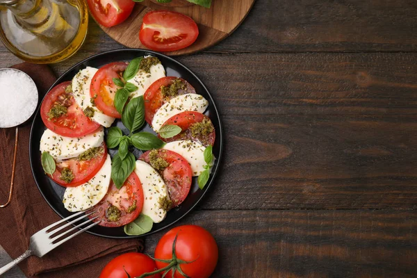 Pesto soslu, çatallı ve ahşap masadaki malzemeli bir tabak lezzetli Caprese salatası. Metin için boşluk