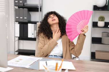 Genç iş kadını ofiste serinlemek için el sallıyor.