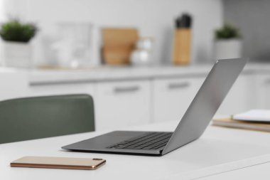 Merkez ofis. Laptop ve akıllı telefon mutfaktaki beyaz masada, mesaj için yer var.