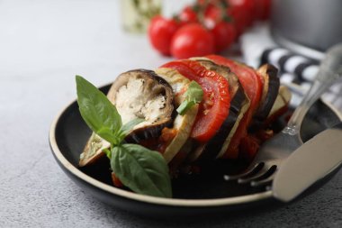 Lezzetli ratatouille, açık gri masada fesleğenle servis edilir.