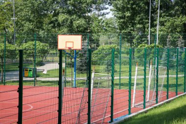 Güneşli bir günde basketbol arka tahtası ve futbol golleri olan çok sporlu bir oyun sahası.