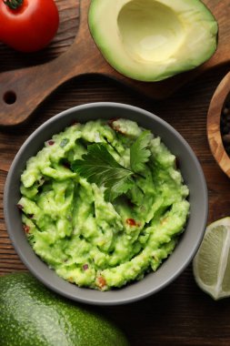 Lezzetli guacamole ve malzemeler ahşap masada, düz yerde.