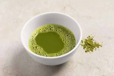 Açık gri desenli masada bir fincan kibrit çayı, yakın plan.